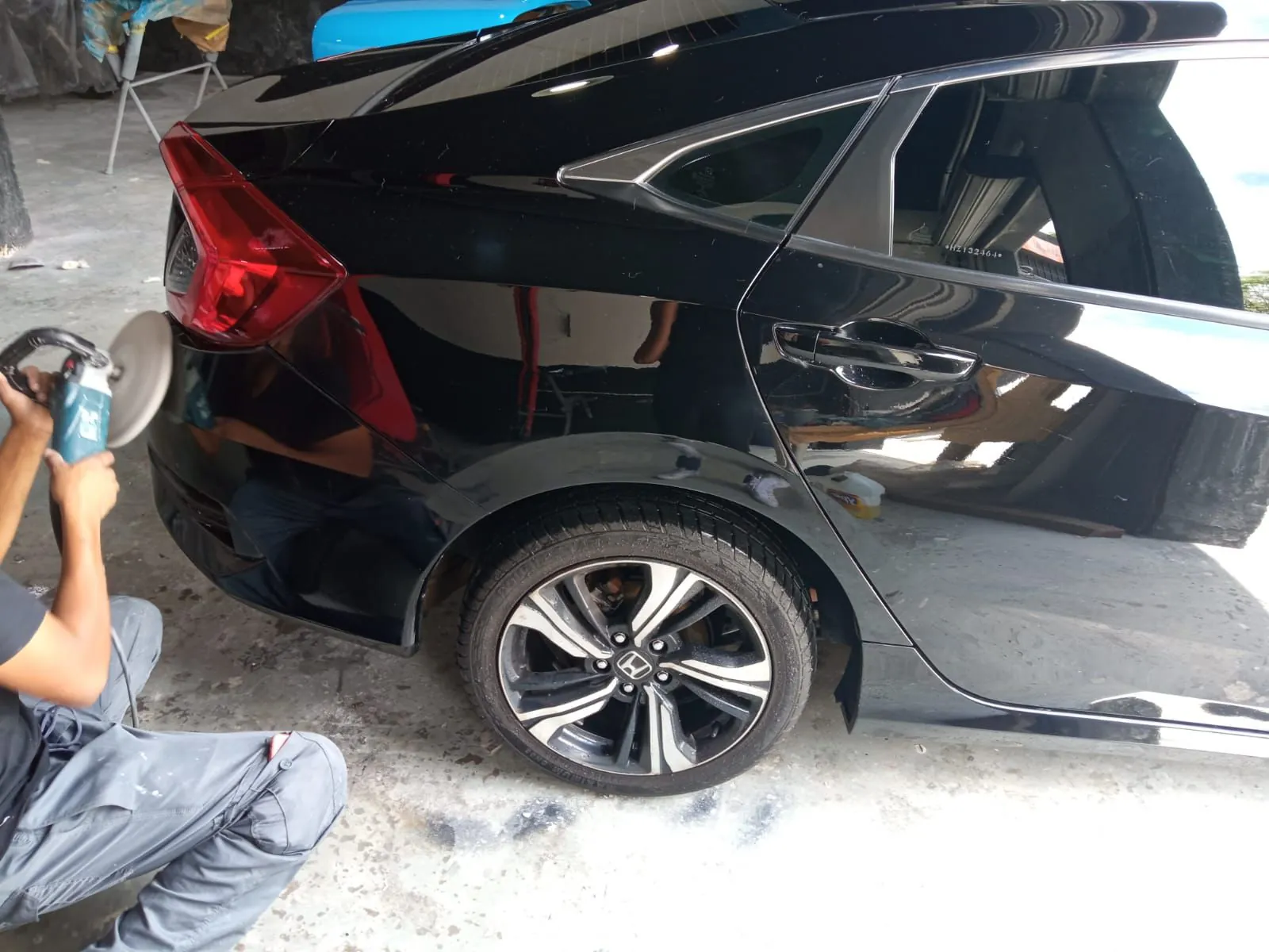 Profissional da Replikar polindo a pintura de um Honda Civic preto com politriz